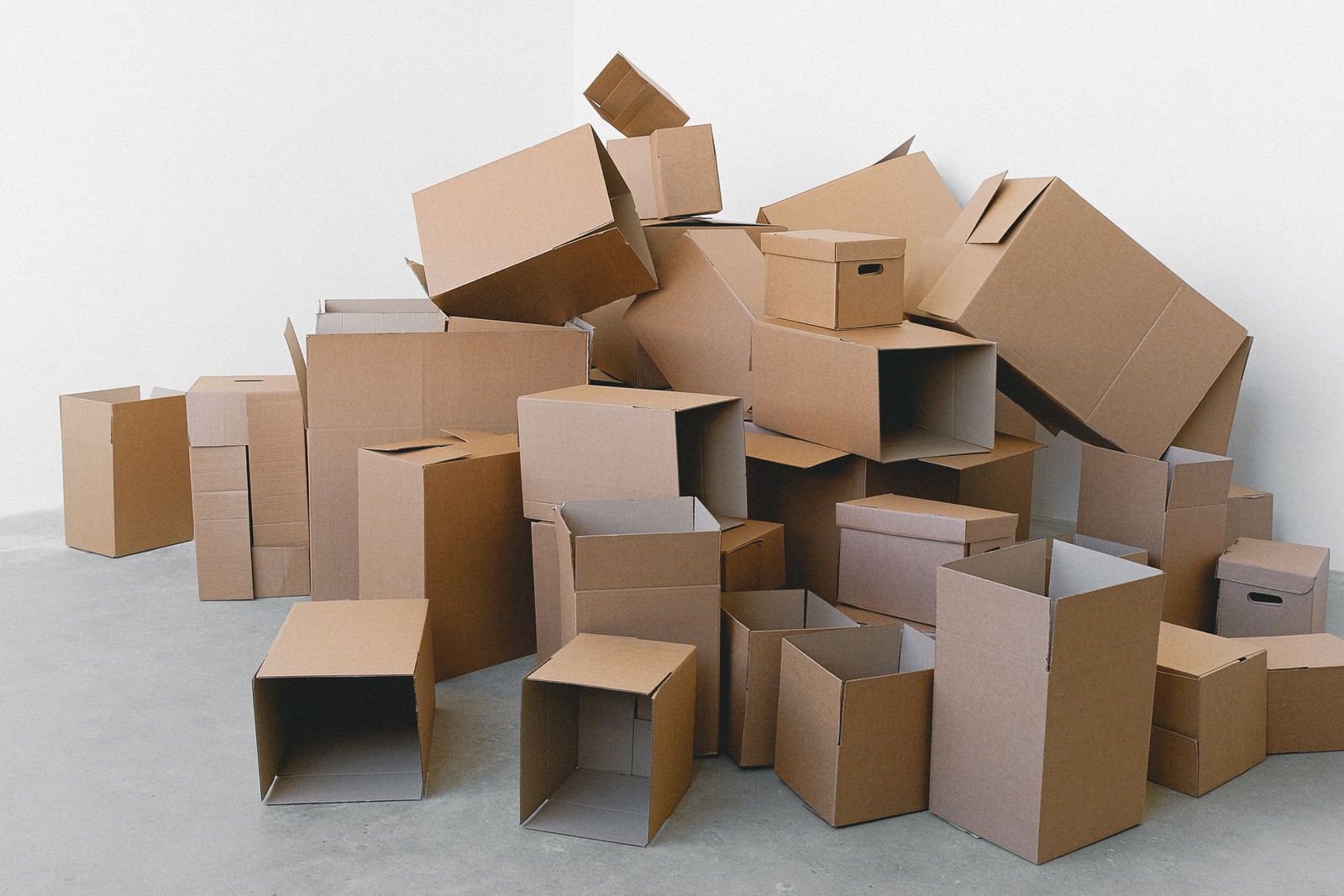 Stacked empty moving boxes in a bare white room, ready for packing.
